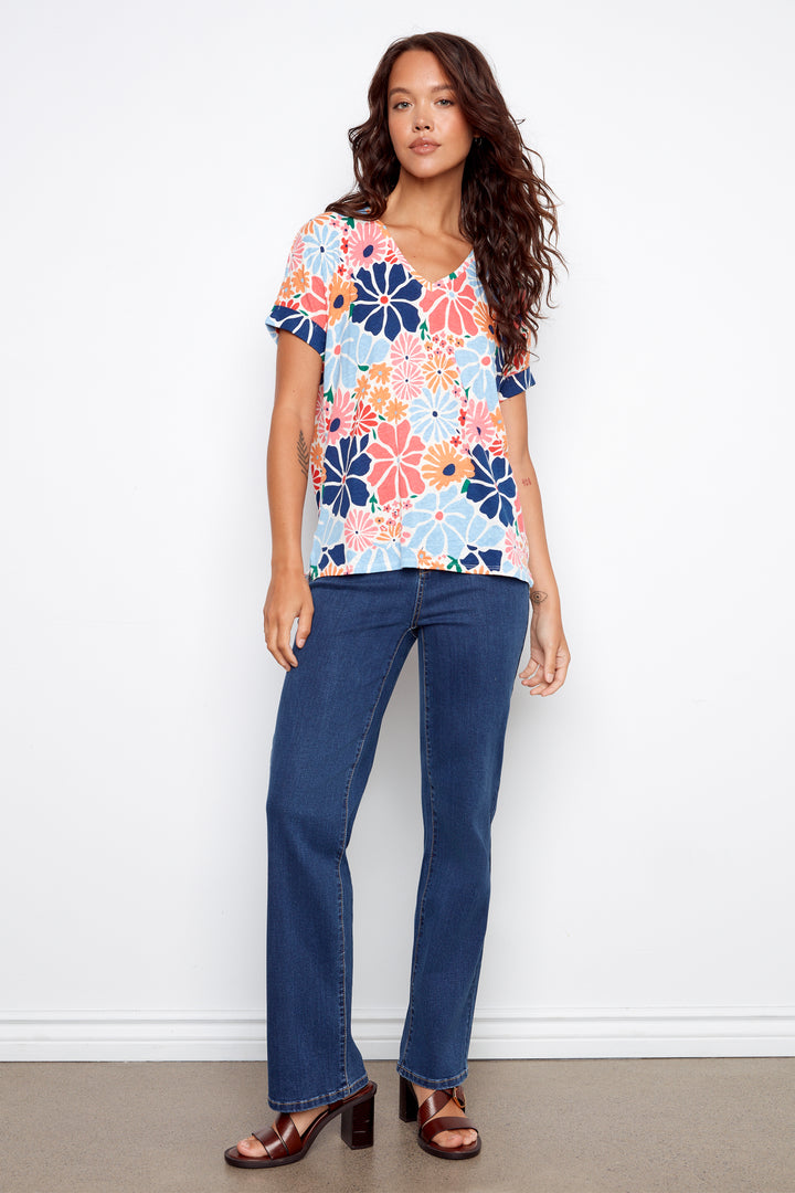 Woman wearing a floral top and blue jeans against a white background