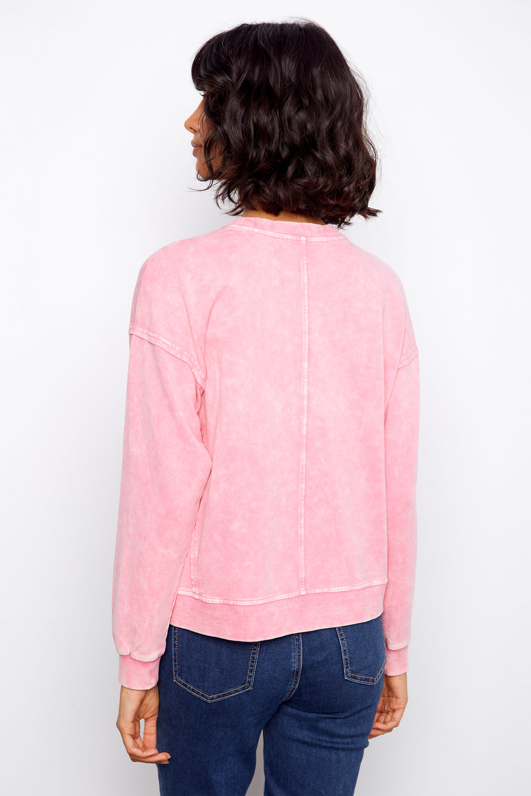 Person wearing a pink sweatshirt and blue jeans on a white background