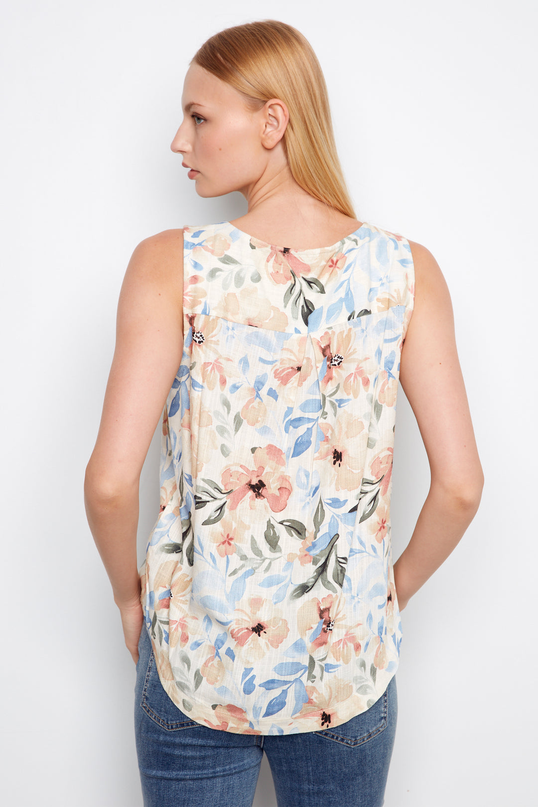 Woman wearing a sleeveless floral top against a white background