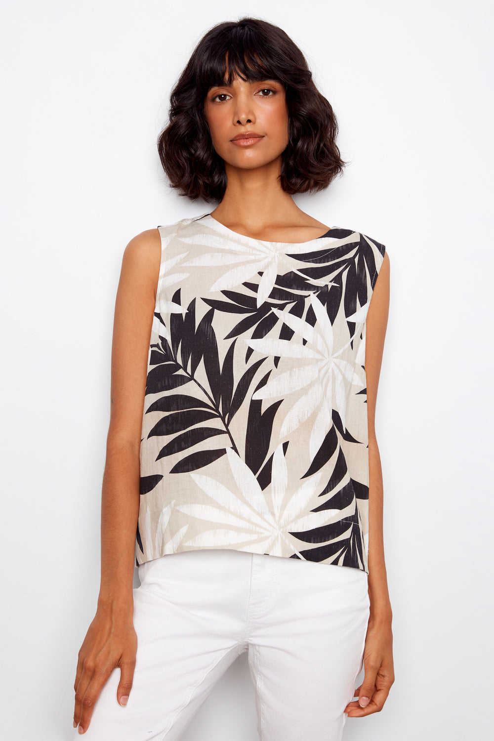 Woman wearing a sleeveless top with black leaf pattern on a white background