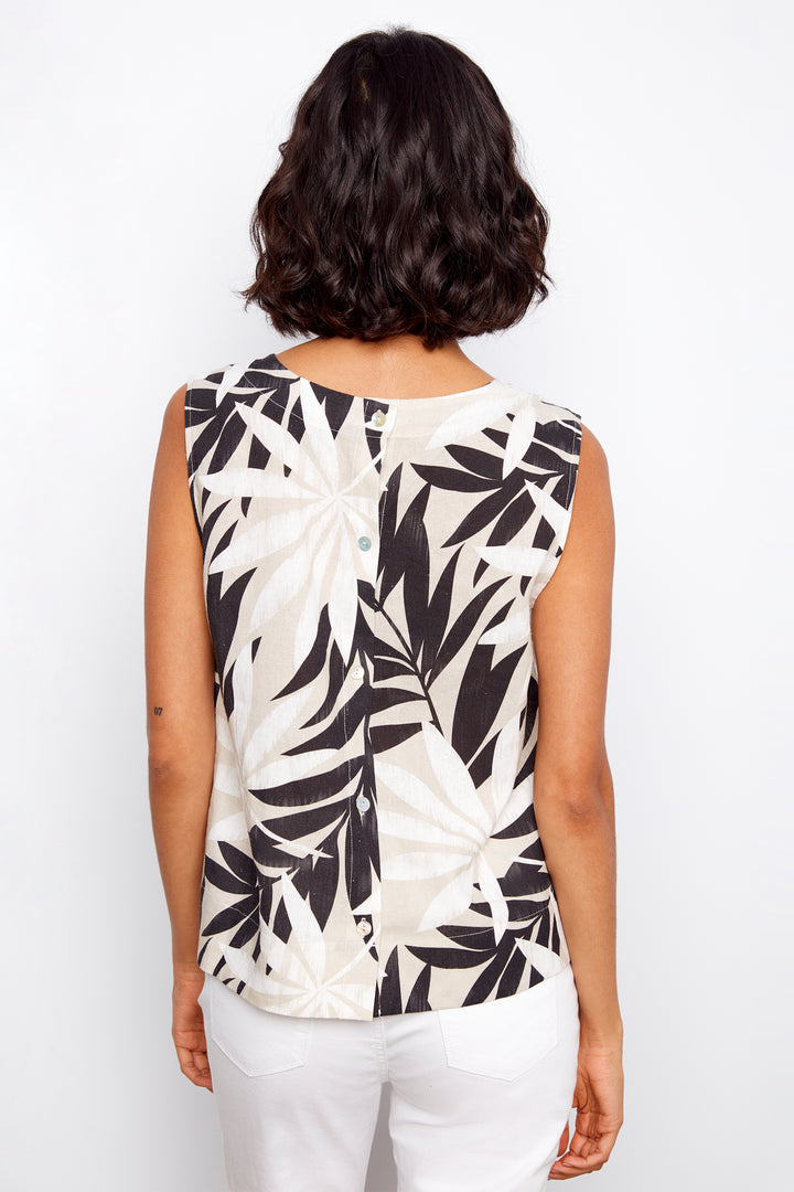 Woman wearing a sleeveless top with black leaf pattern on a white background