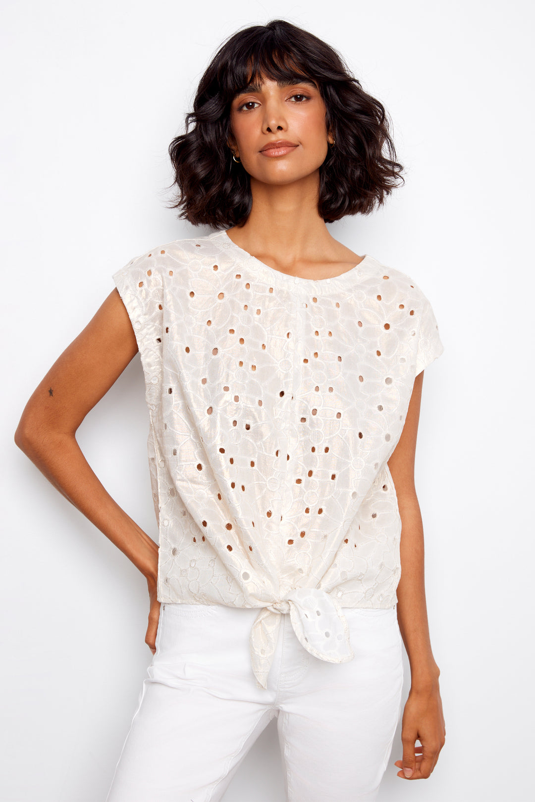 Woman wearing a white blouse with small patterns on a plain background