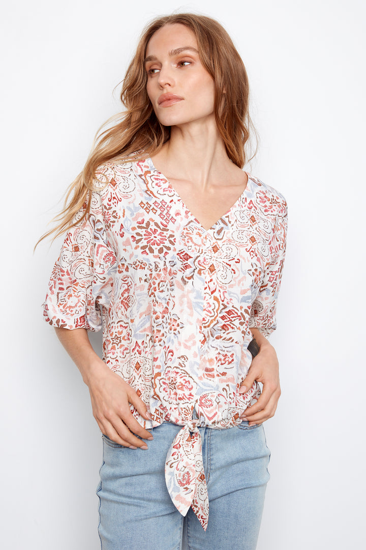 Woman wearing a floral blouse and jeans against a white background