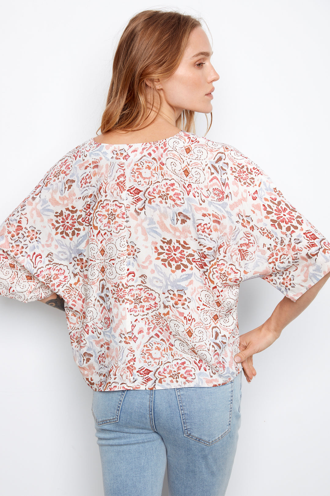 Woman wearing a floral blouse and light blue jeans on a white background