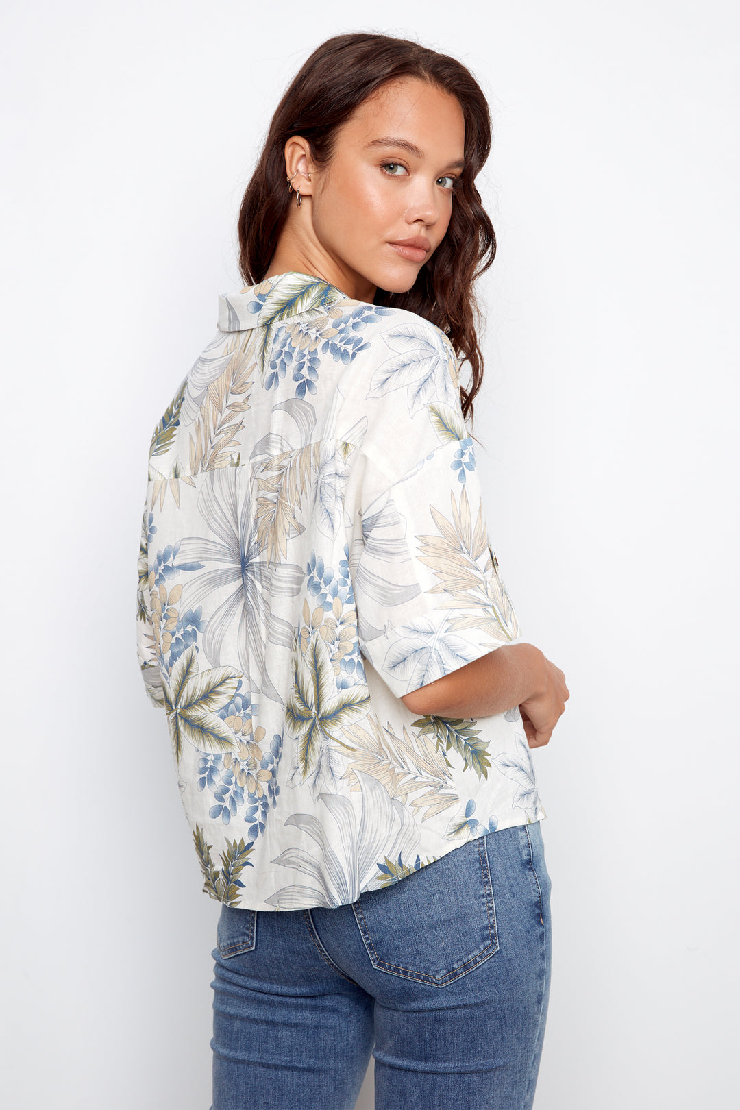 Woman wearing a floral blouse and jeans on a white background