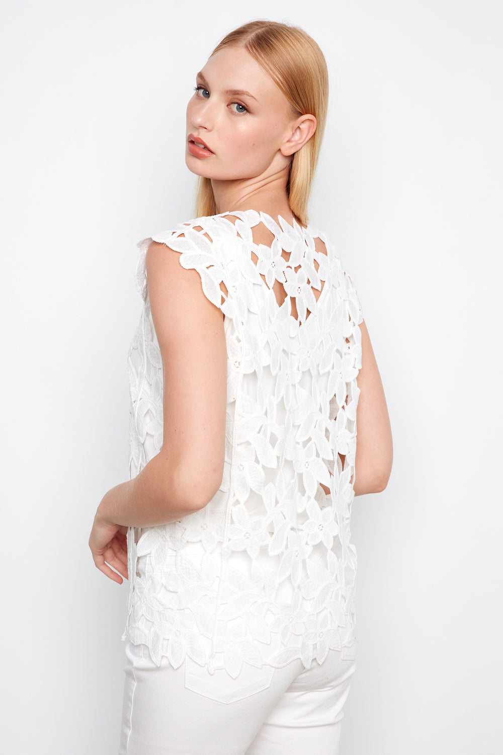 Woman wearing a white lace top against a white background
