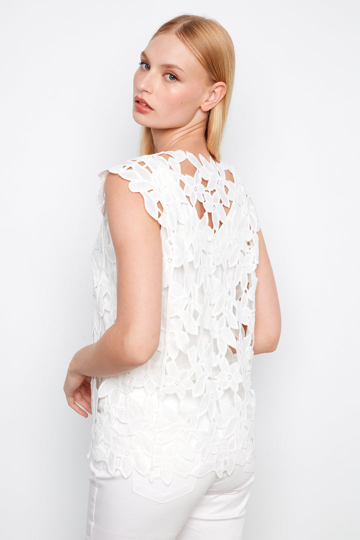 Woman wearing a white lace top against a white background