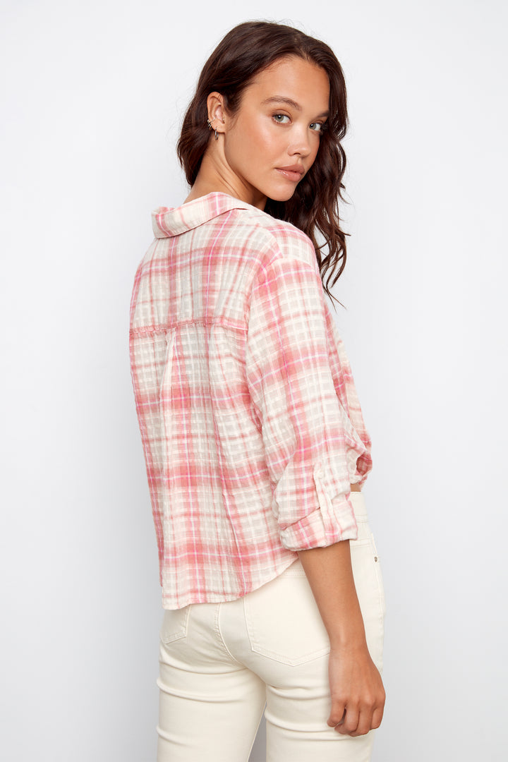 Woman wearing a pink and white plaid shirt against a white background