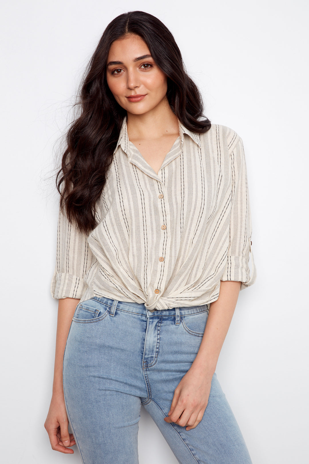 Woman wearing a striped blouse and jeans against a white background