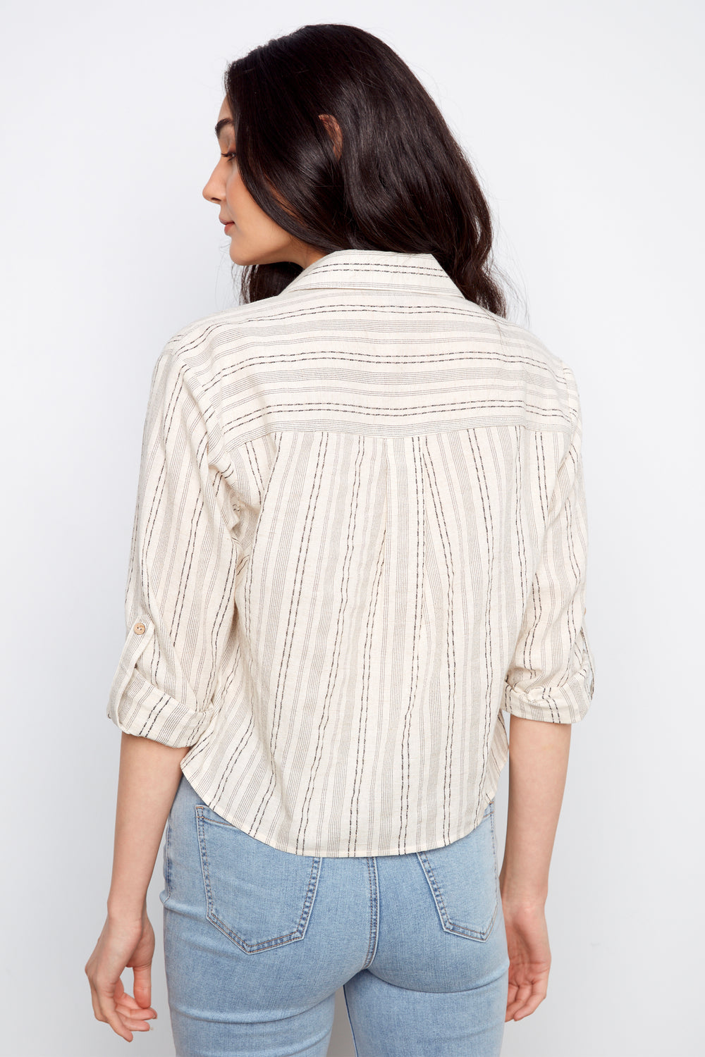 Woman wearing a striped shirt and jeans against a white background