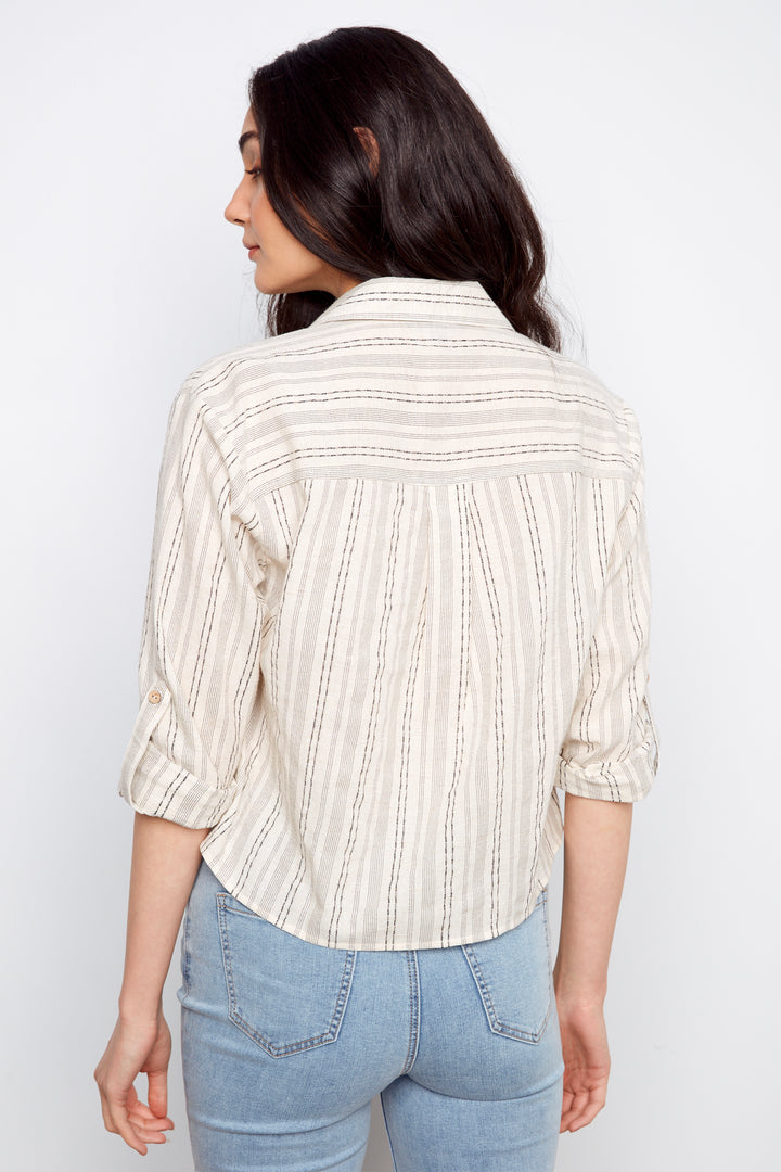 Woman wearing a striped shirt and jeans against a white background