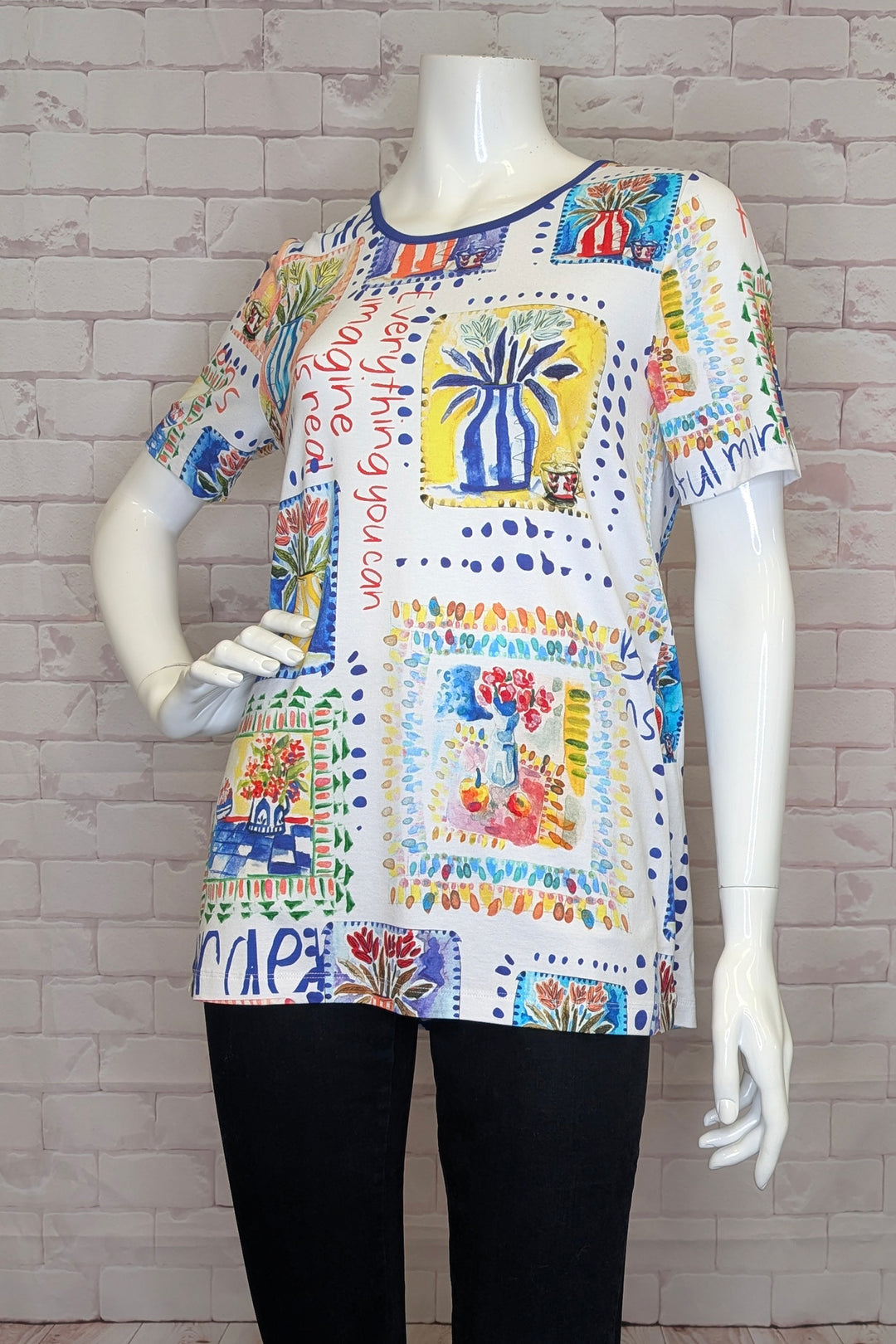 Colorful tunic top with flowers print on a mannequin against a brick wall background