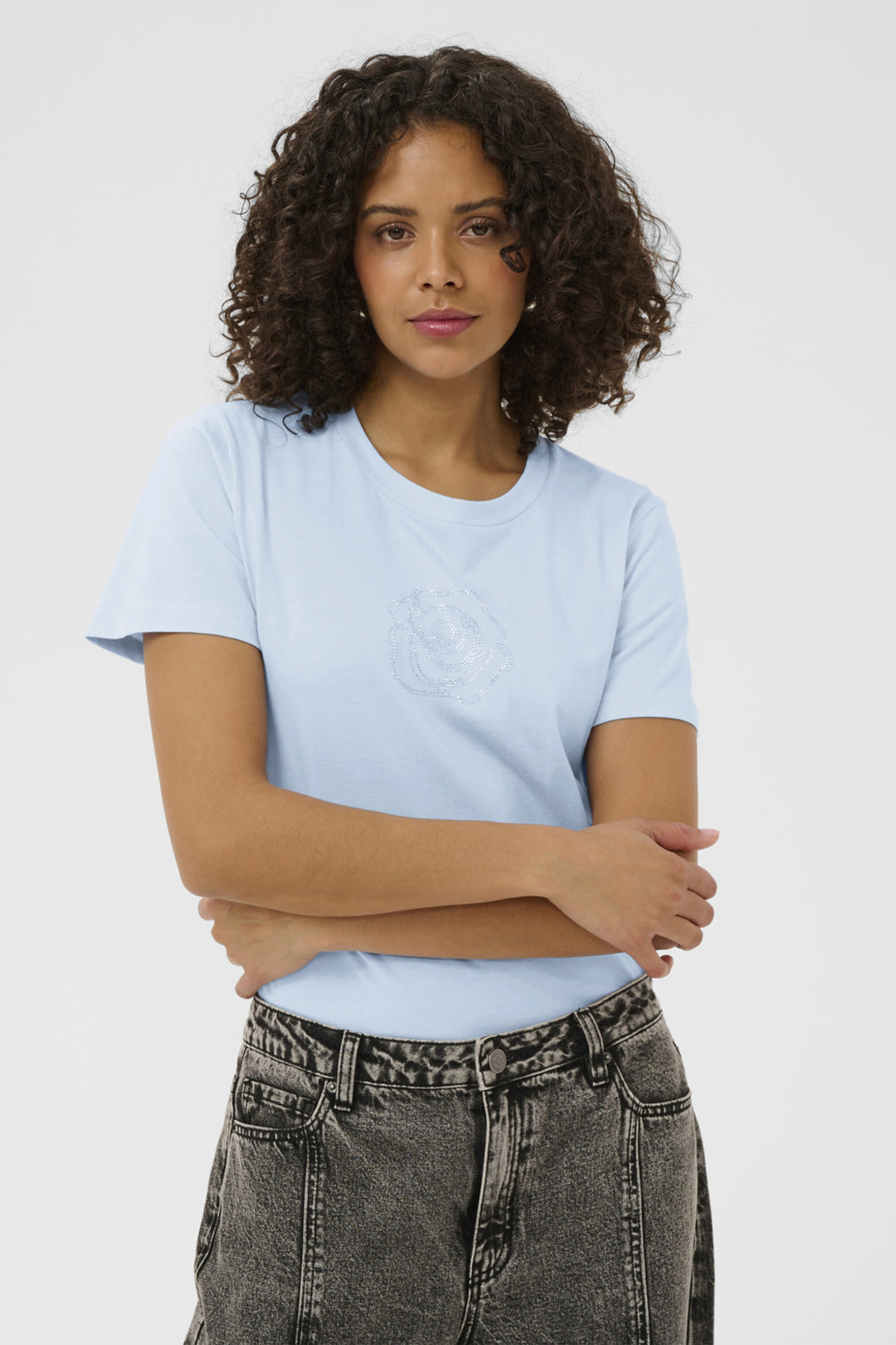Woman wearing a light blue t-shirt and dark jeans against a white background