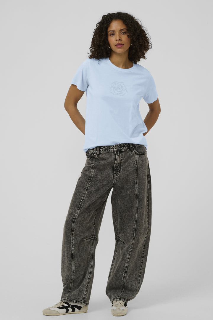 Person wearing a light blue t-shirt and black jeans on a plain background