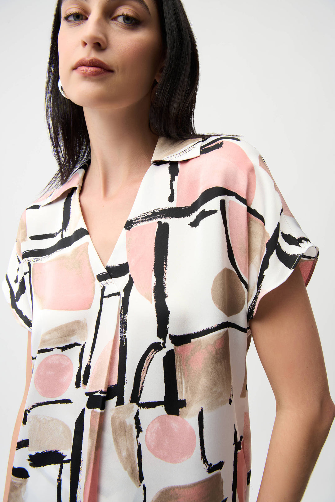 Woman wearing a patterned shirt with abstract design on a plain background