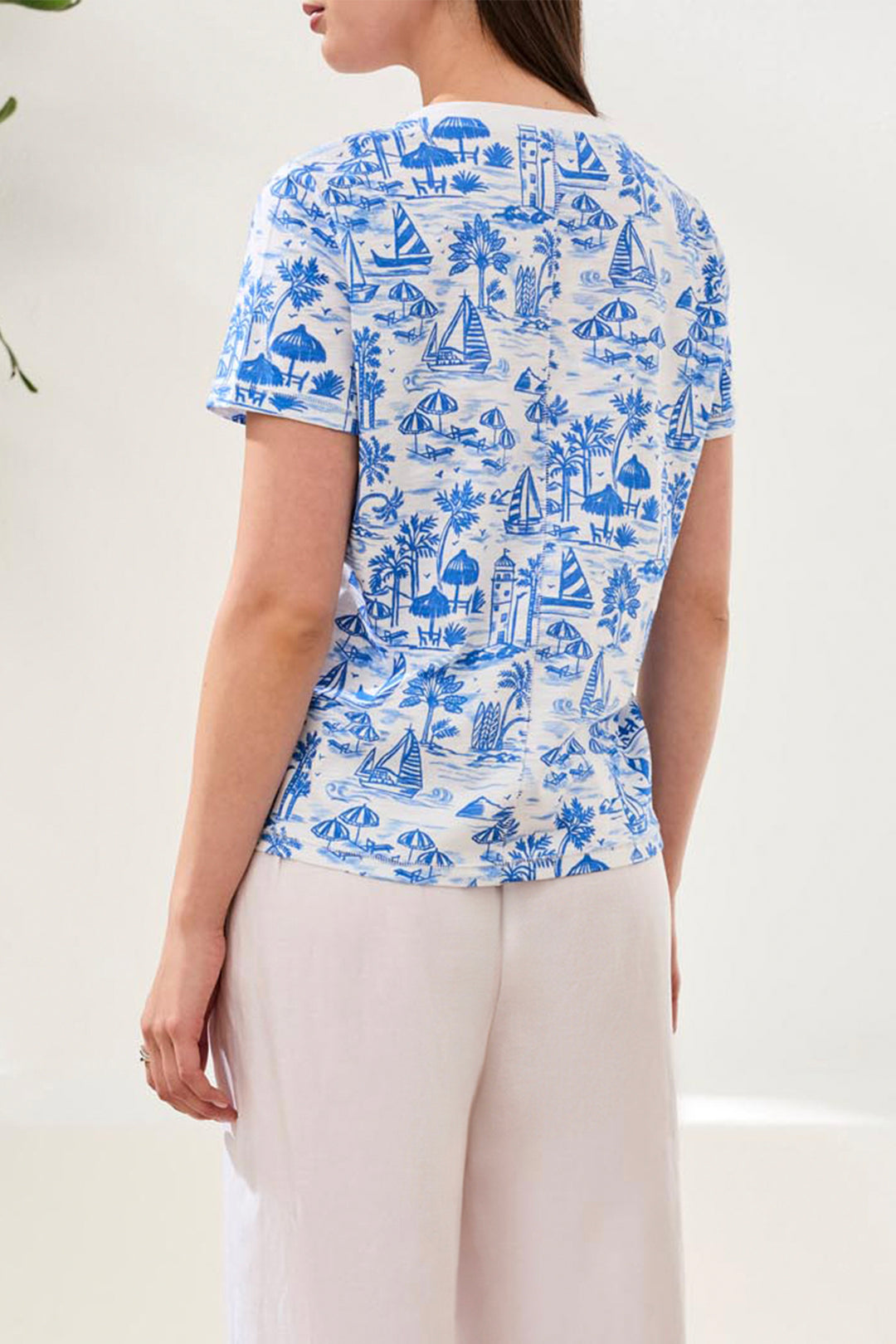 Woman wearing a blue and white patterned shirt with beige pants on a light background
