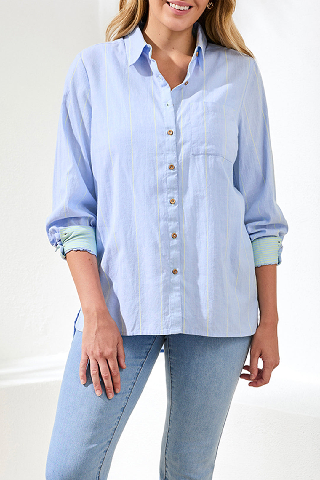 Woman wearing a light blue striped shirt and jeans against a white background