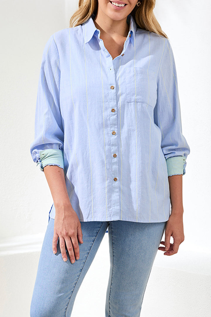 Woman wearing a light blue striped shirt and jeans against a white background