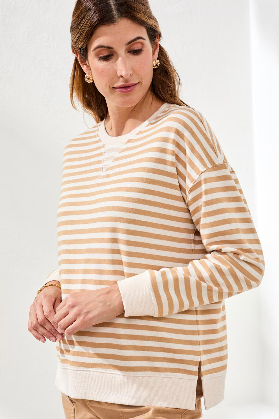 Woman wearing a beige and white striped sweater on a white background