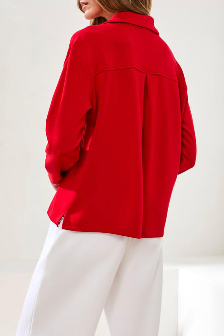 Person wearing a red jacket and white pants on a light background