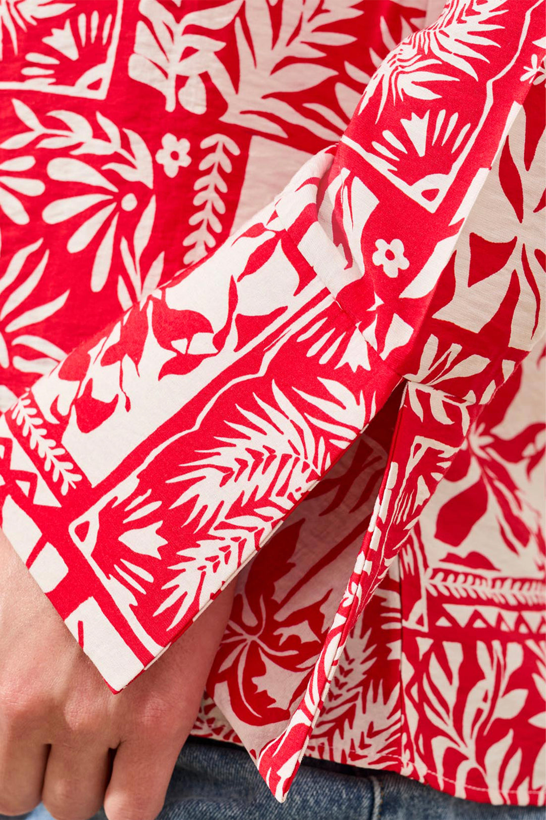 Red and white patterned shirt with a hand adjusting the collar.