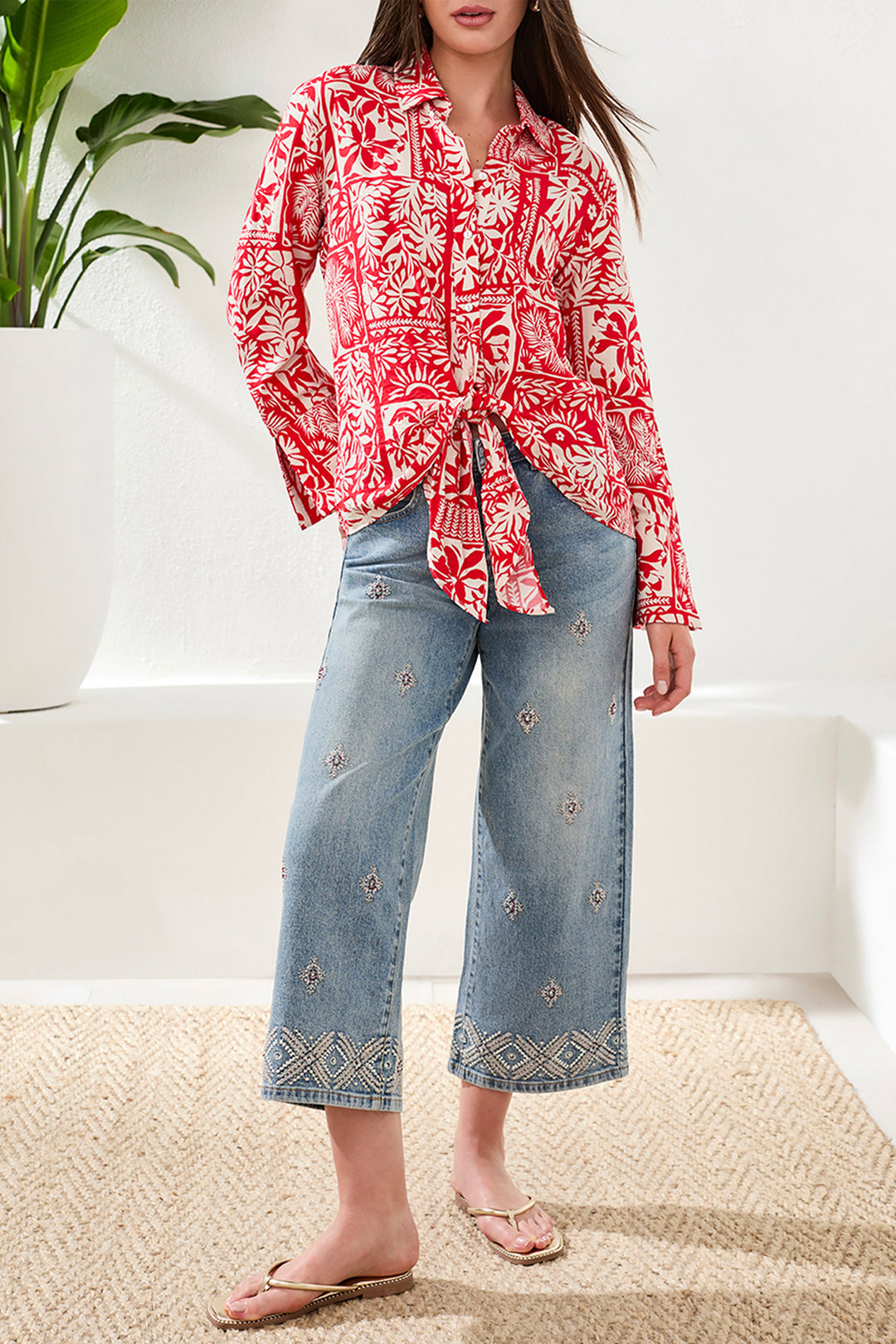 Person wearing a red floral blouse and blue jeans with a white background
