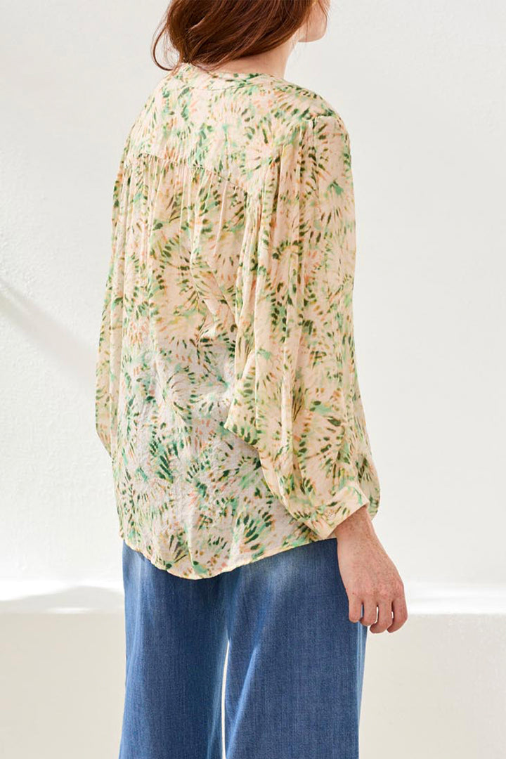 Woman wearing a floral blouse and blue pants on a white background