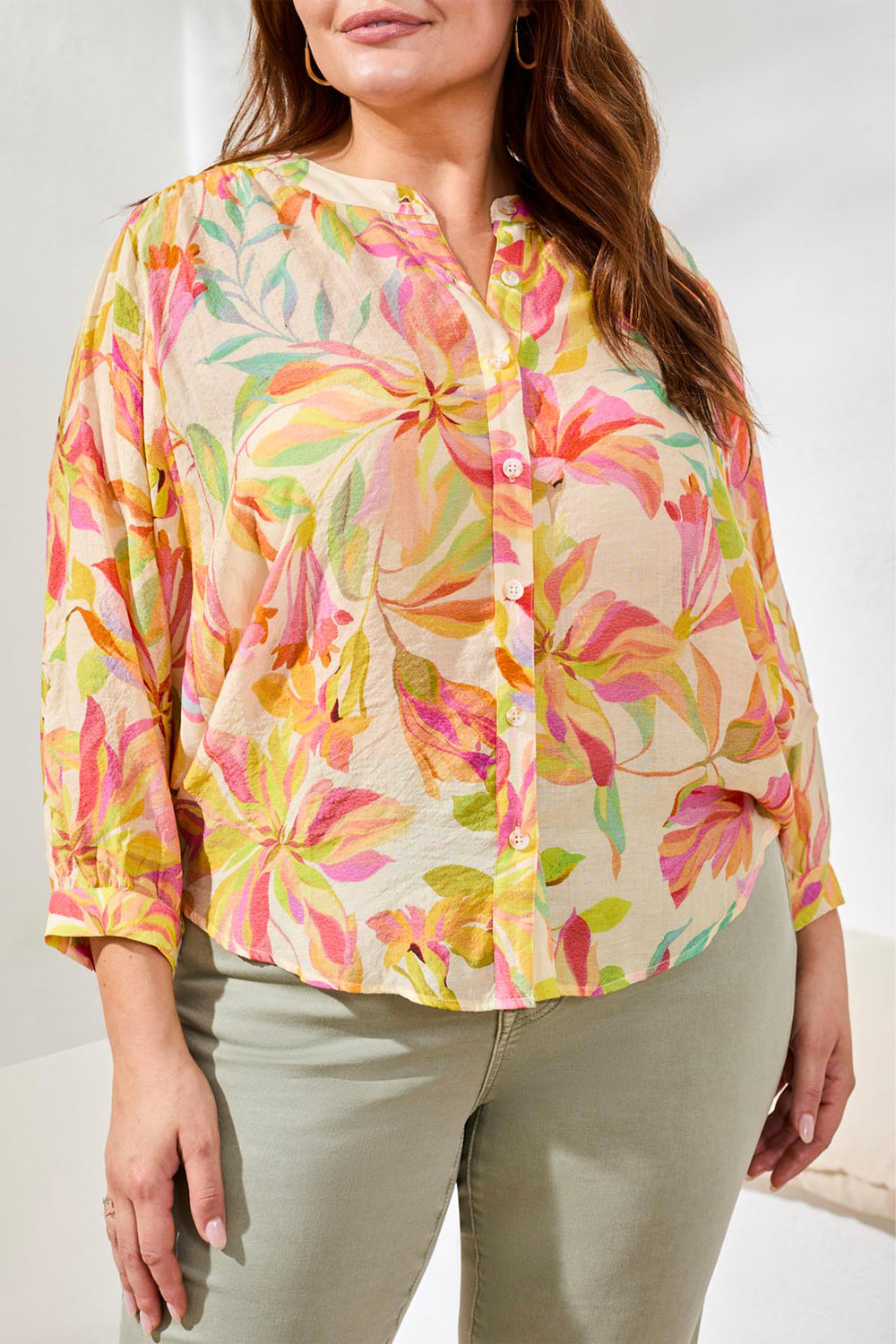 Woman wearing a colorful floral blouse against a white background