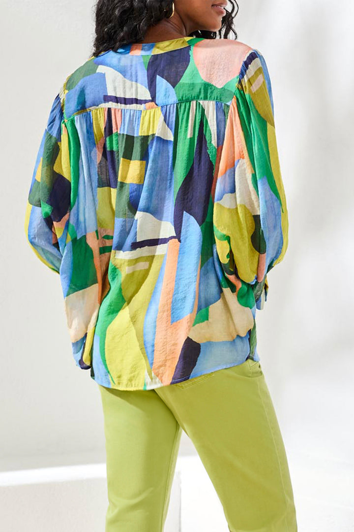 Person wearing a colorful patterned top and green pants on a white background
