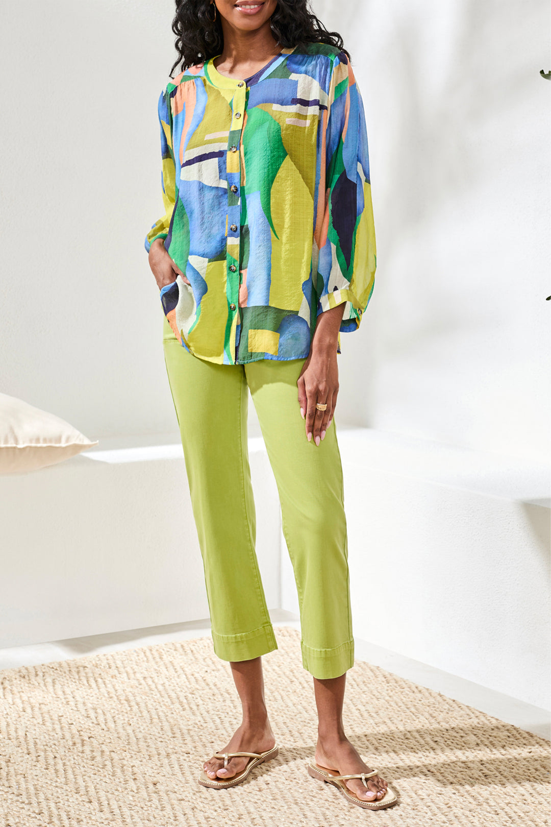 Woman wearing a colorful blouse and green pants on a white background