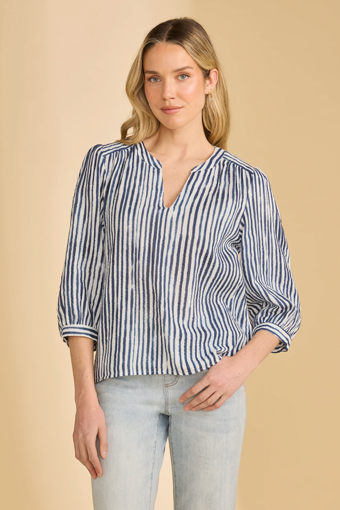 Woman wearing a blue and white striped shirt against a beige background