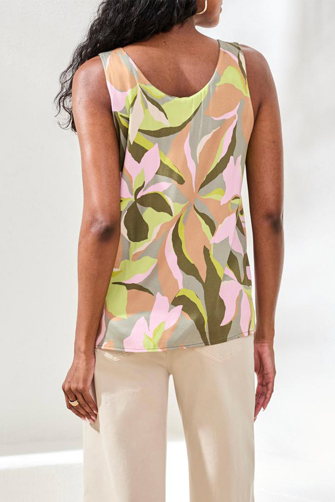 Woman wearing a sleeveless top with a floral pattern on a plain background