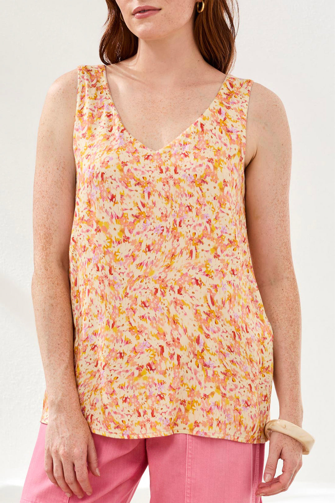 Woman wearing a colorful sleeveless top with a white background