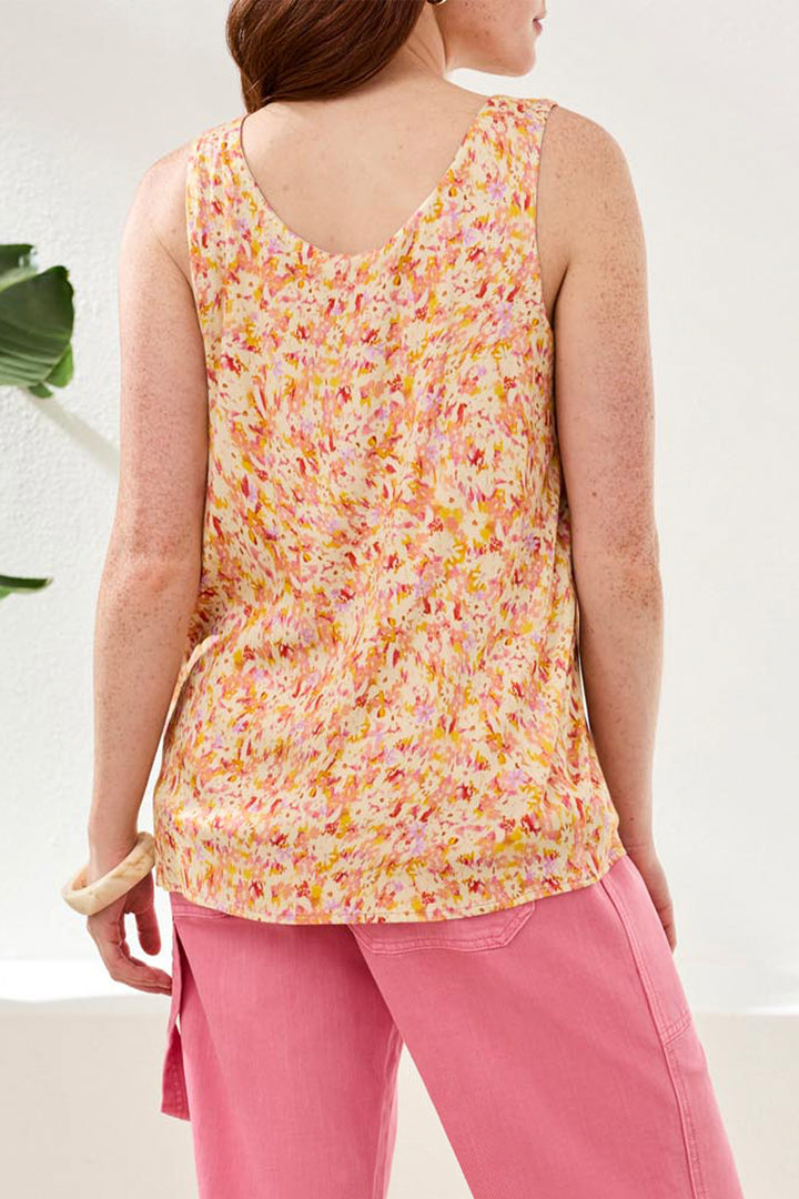 Person wearing a floral sleeveless top and pink pants on a white background