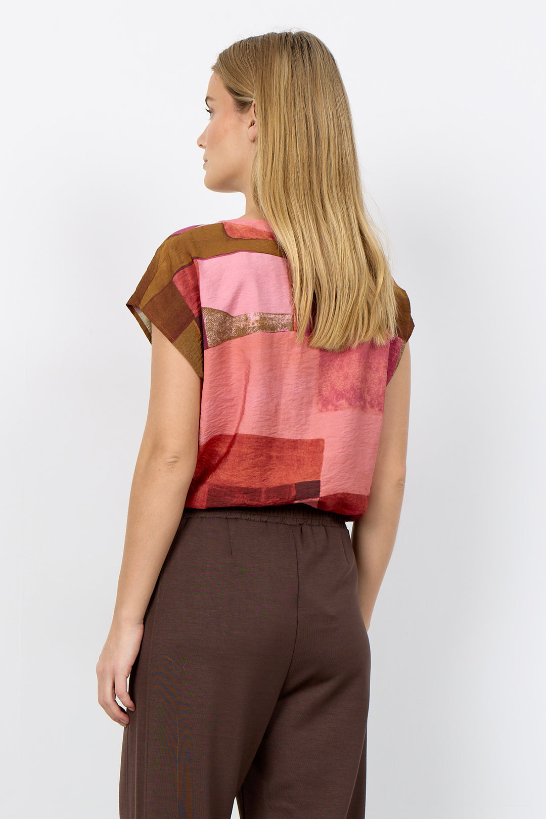 Woman wearing a colorful top with abstract patterns on a white background