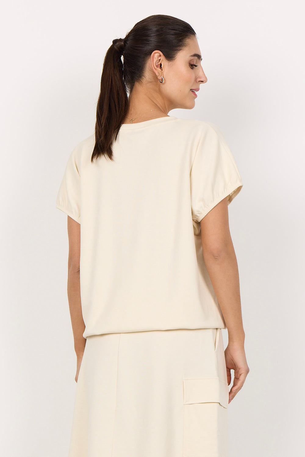 woman wearing a cream coloured t-shirt on white background
