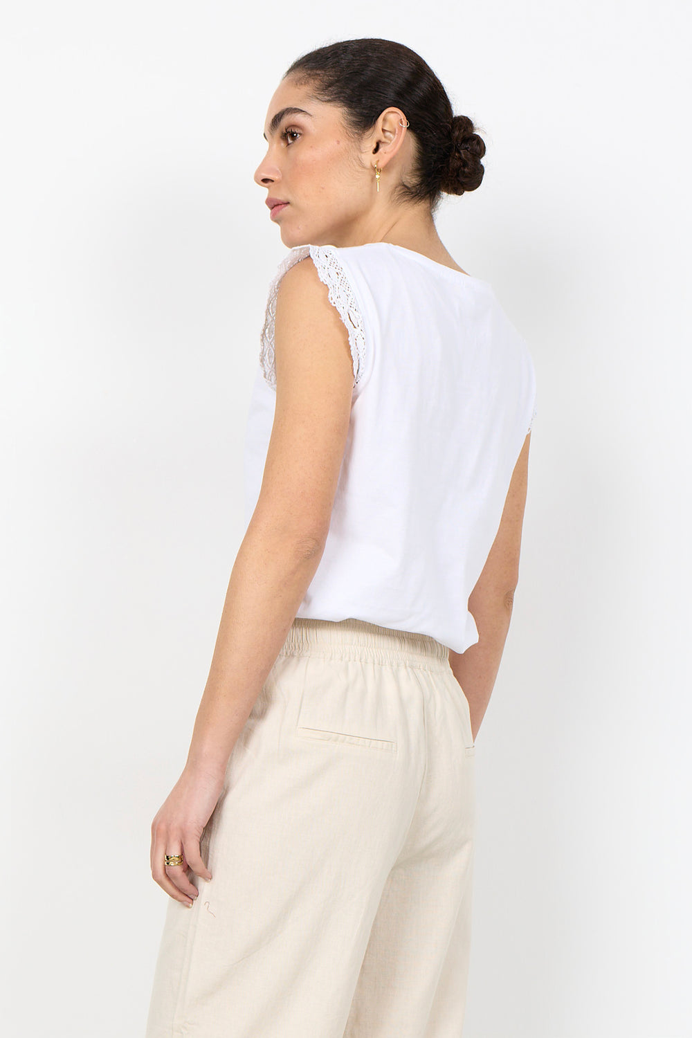 woman wearing white t-shirt with lace details on sleeves on a white background. 