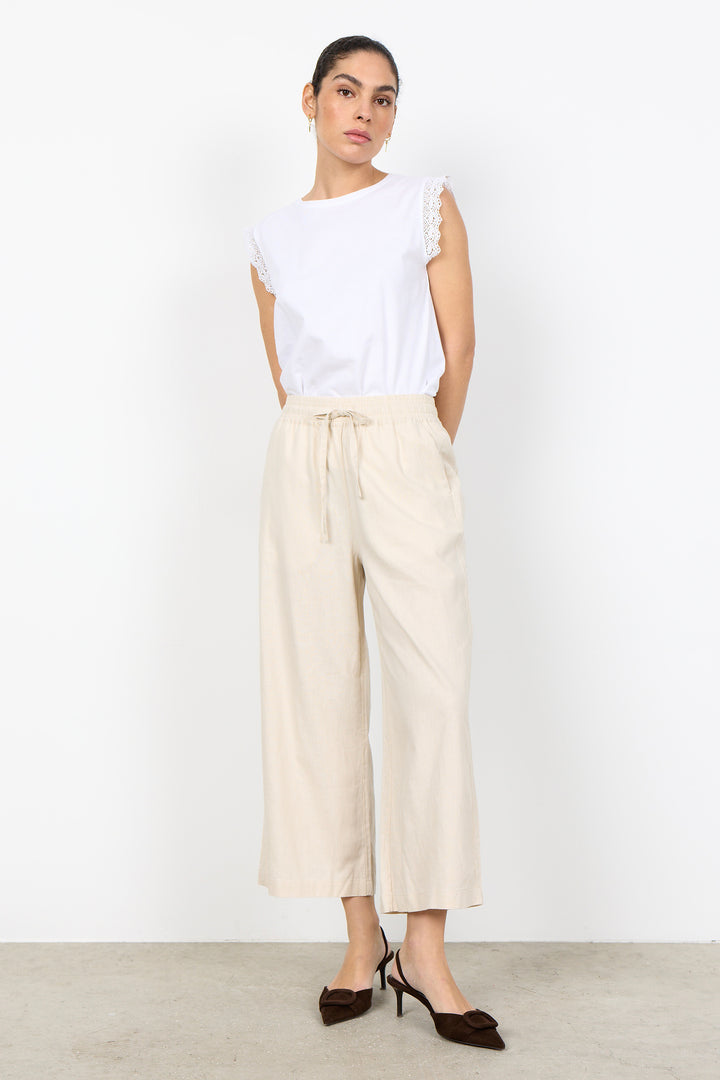 woman wearing white t-shirt with lace details on sleeves on a white background. 