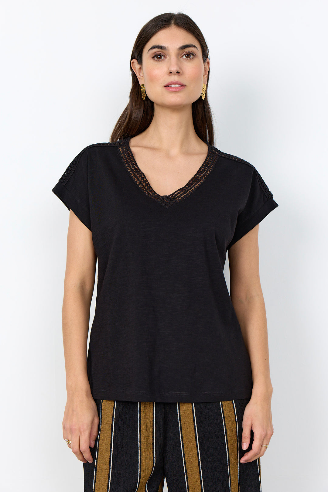 woman wearing a casual t-shirt with lace detail along neckline on a white background. 