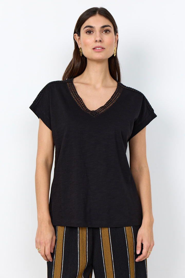 woman wearing a casual t-shirt with lace detail along neckline on a white background. 