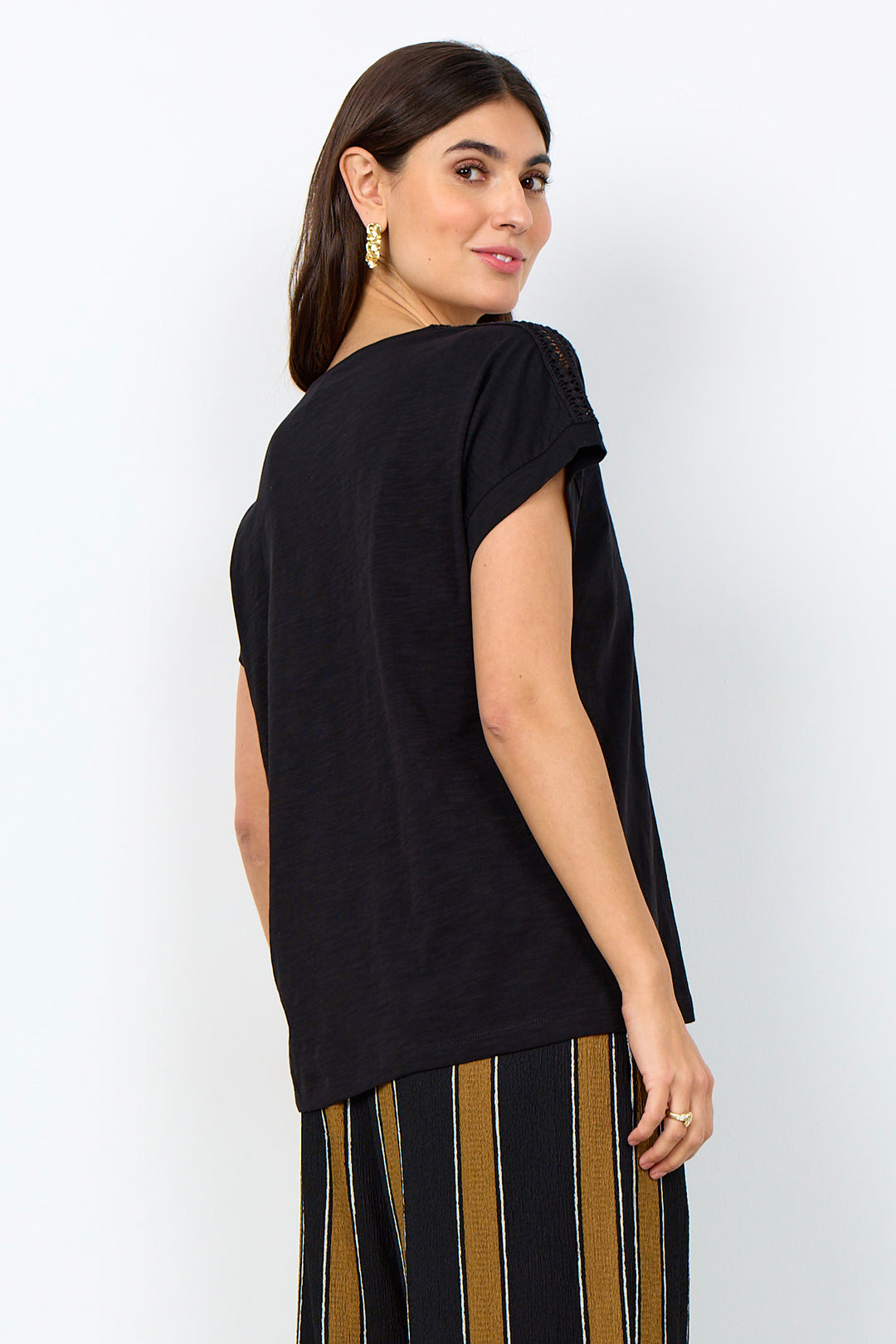 woman wearing a casual t-shirt with lace detail along neckline on a white background. 