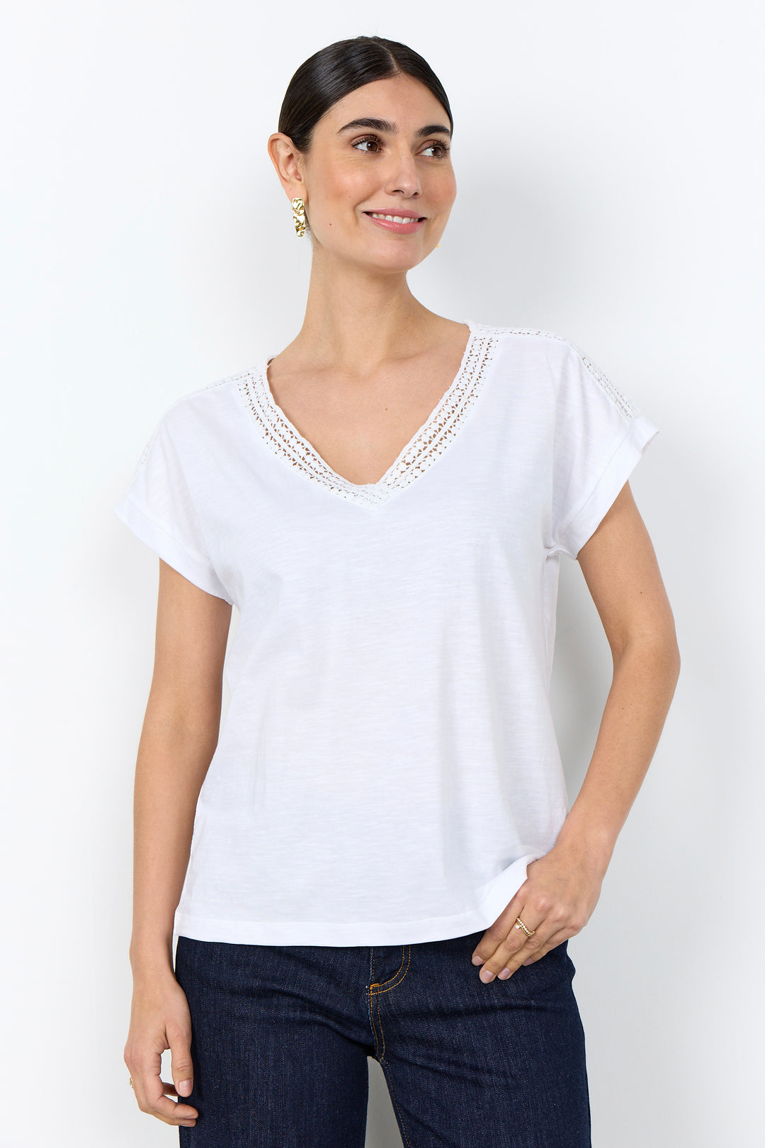 woman wearing a casual t-shirt with lace detail along neckline on a white background. 