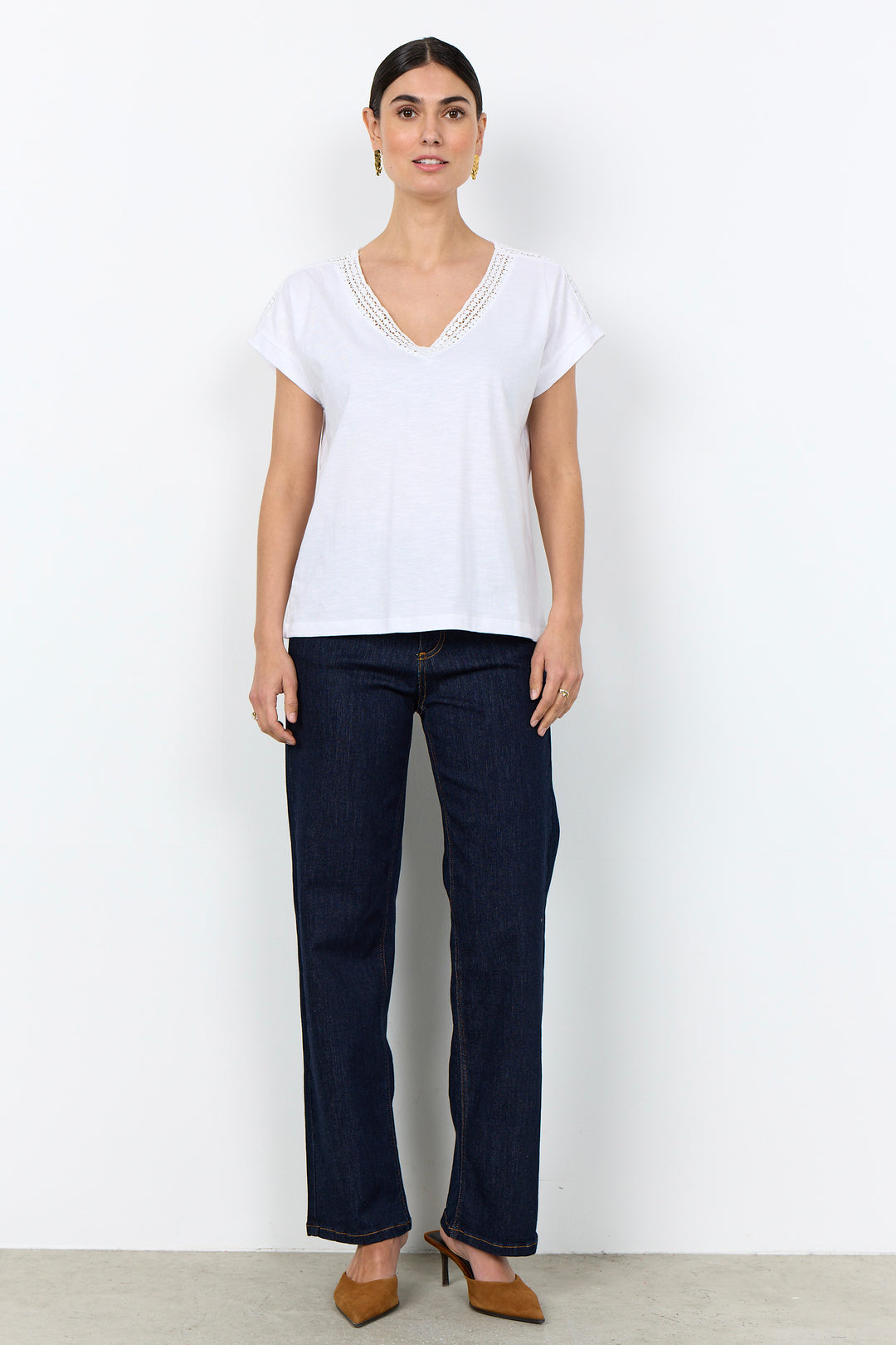 woman wearing a casual t-shirt with lace detail along neckline on a white background. 