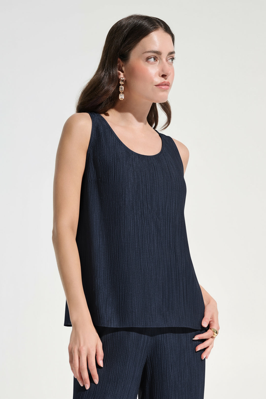 Woman wearing a dark blue sleeveless top and pants on a white background