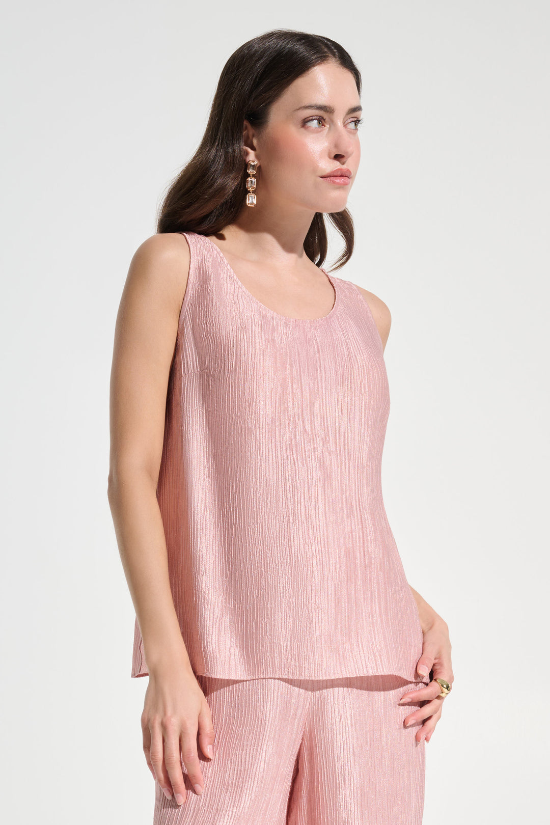Woman wearing a pink sleeveless top and pants on a white background