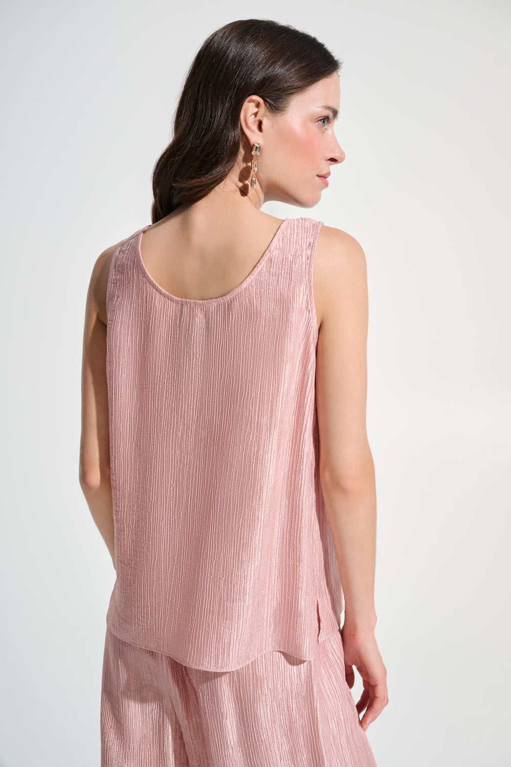 Woman wearing a pink sleeveless top and pants on a white background