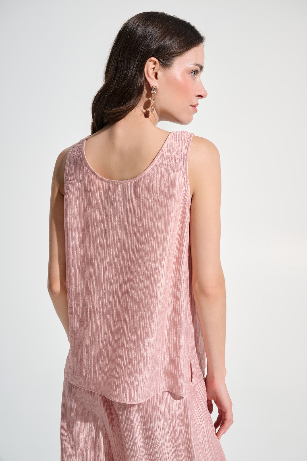 Woman wearing a pink sleeveless top and pants on a white background