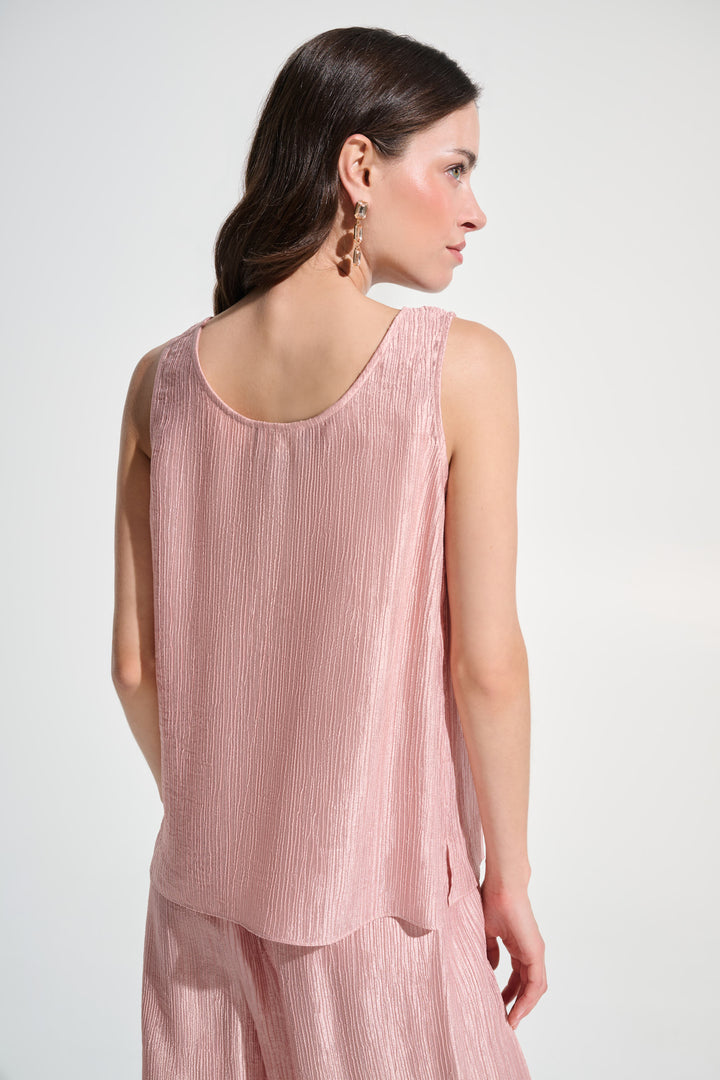 Woman wearing a pink sleeveless top and pants on a white background