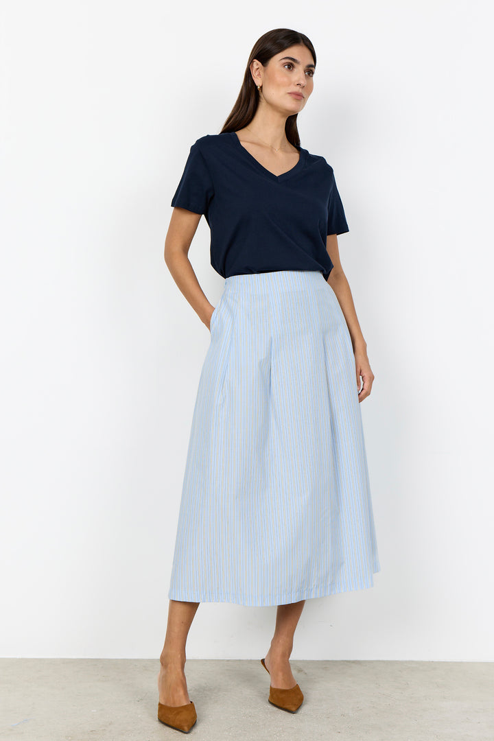 Woman wearing a navy top and light blue skirt on a white background