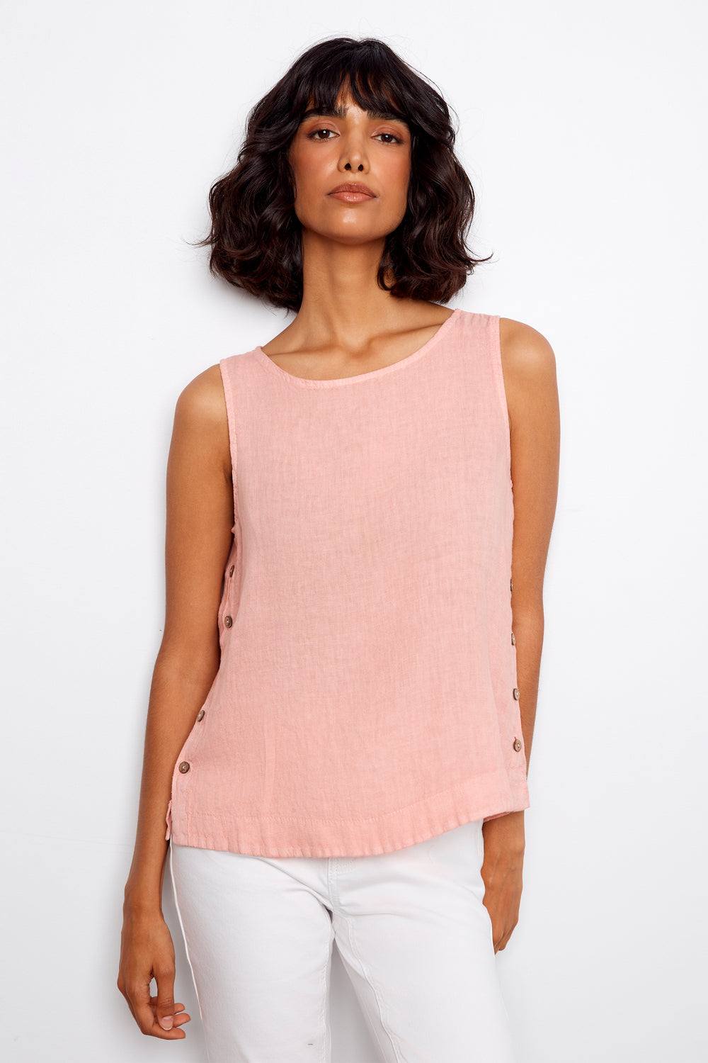 Woman wearing a pink sleeveless top with buttons on a white background